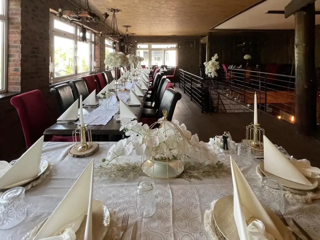 Festlich gedeckte Hochzeitstafel mit weißen Blumen, Kerzen und Goldakzenten im Veranstaltungsraum des TROY Hennef