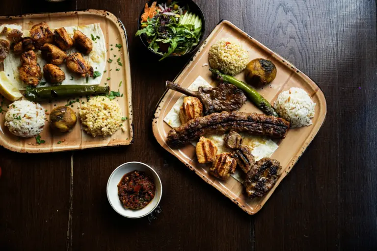 Gedeckter Tisch von oben mit zwei Grillplatten, Salat und scharfer Paste – TROY Restaurant Hennef