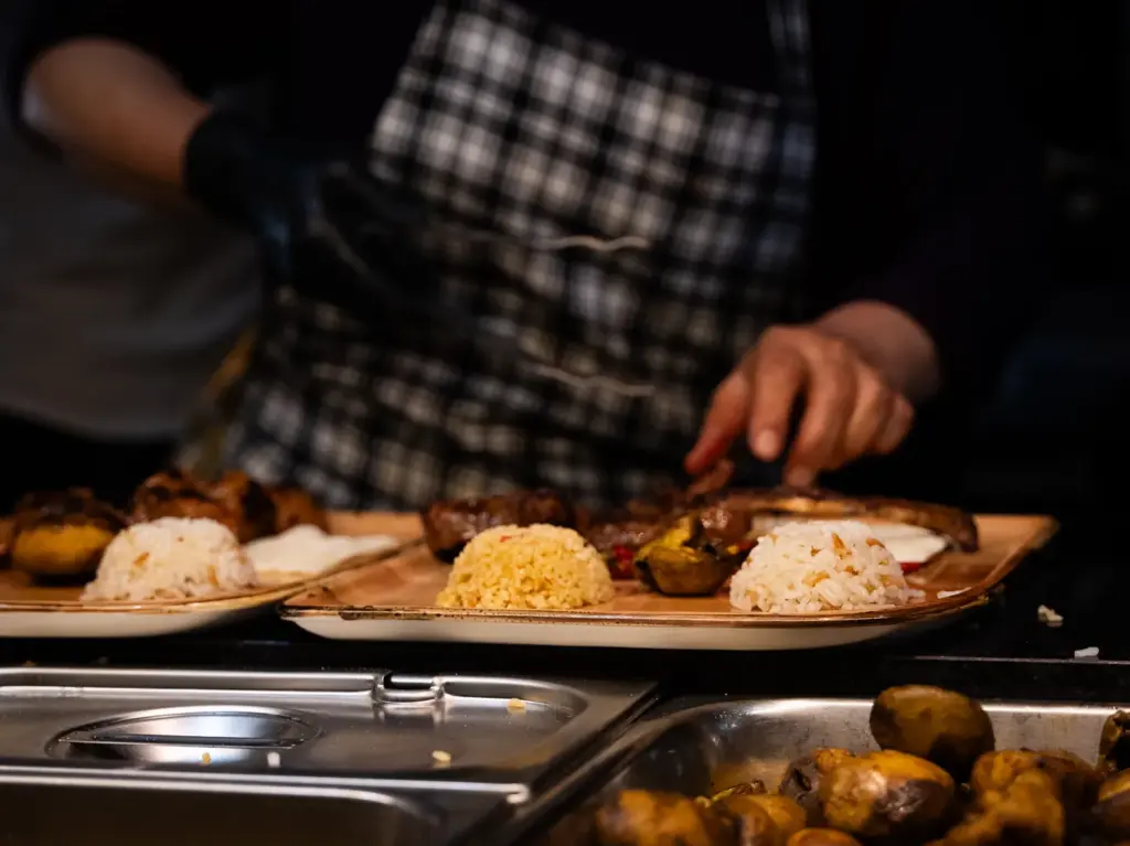 Koch richtet Grillteller mit Reis und Bulgur an – Küche des TROY Restaurant Hennef